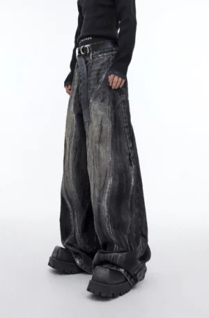 Front view of graphite black distressed flared wide leg denim jeans with washed gradient finish styled with a black knit top and platform boots