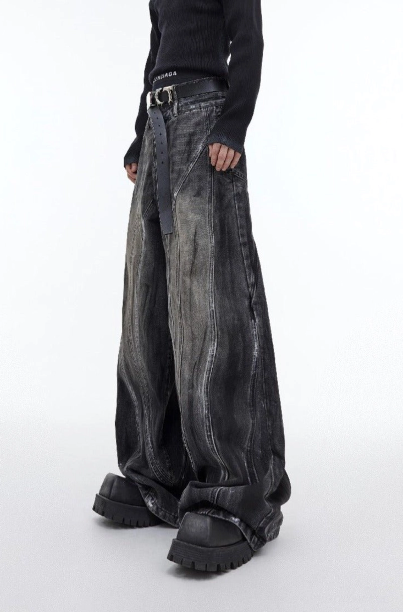 Front view of graphite black distressed flared wide leg denim jeans with washed gradient finish styled with a black knit top and platform boots