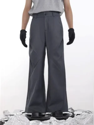 Dark graphite grey wide-leg tailored trousers shown from the front with geometric diagonal seams, belt loops, and a button fly