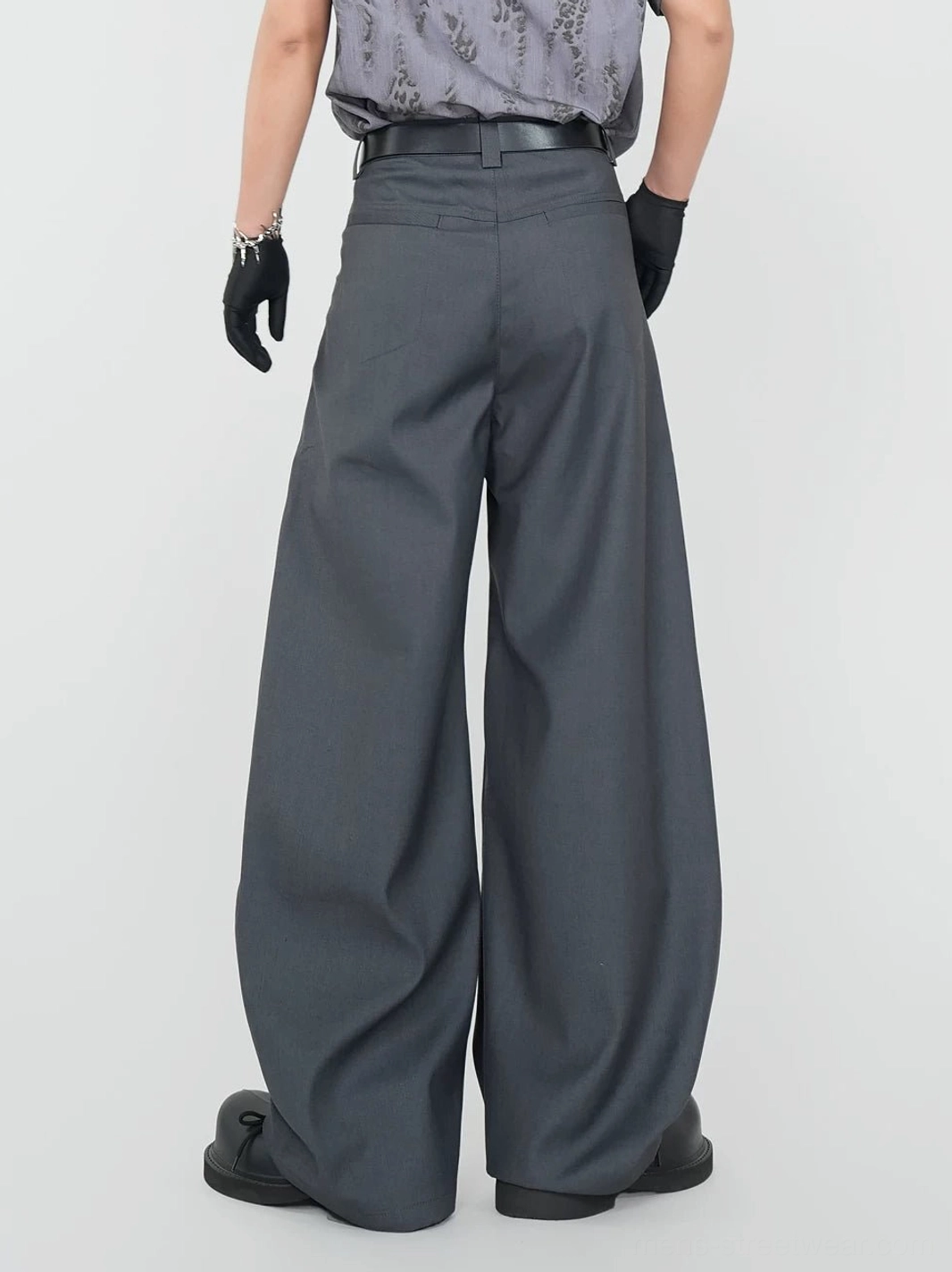 Back view of graphite wide-leg dress pants with tailored rear waist darts, flat back pockets, and floor-length oversized hems