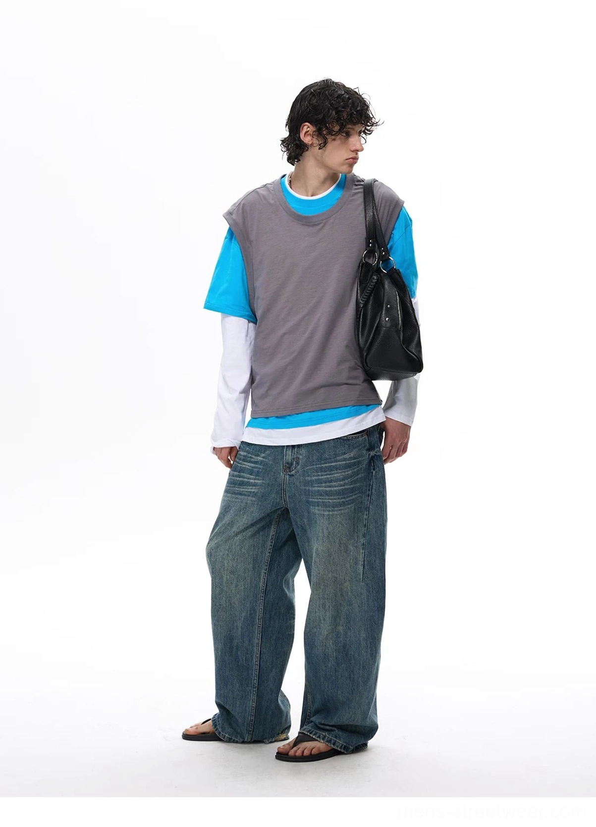 Side view of a gray blue and white faux layered vest tee top with loose jeans, slides, and a black crossbody shoulder bag