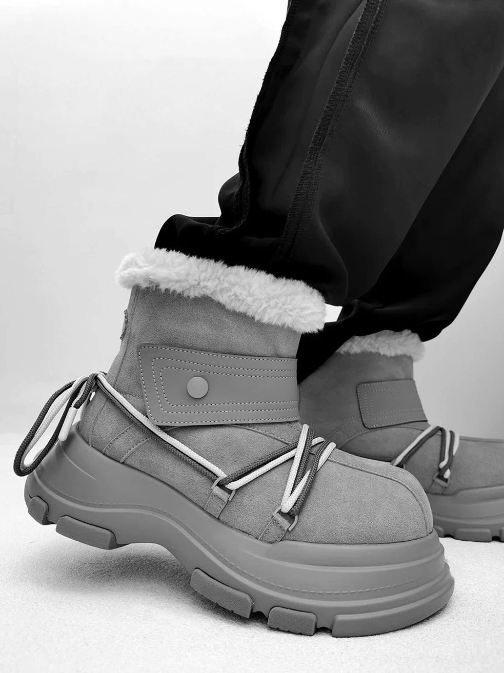 Gray chunky platform shearling snow boots with white contrast wraparound laces and faux-fur collar worn with black trousers