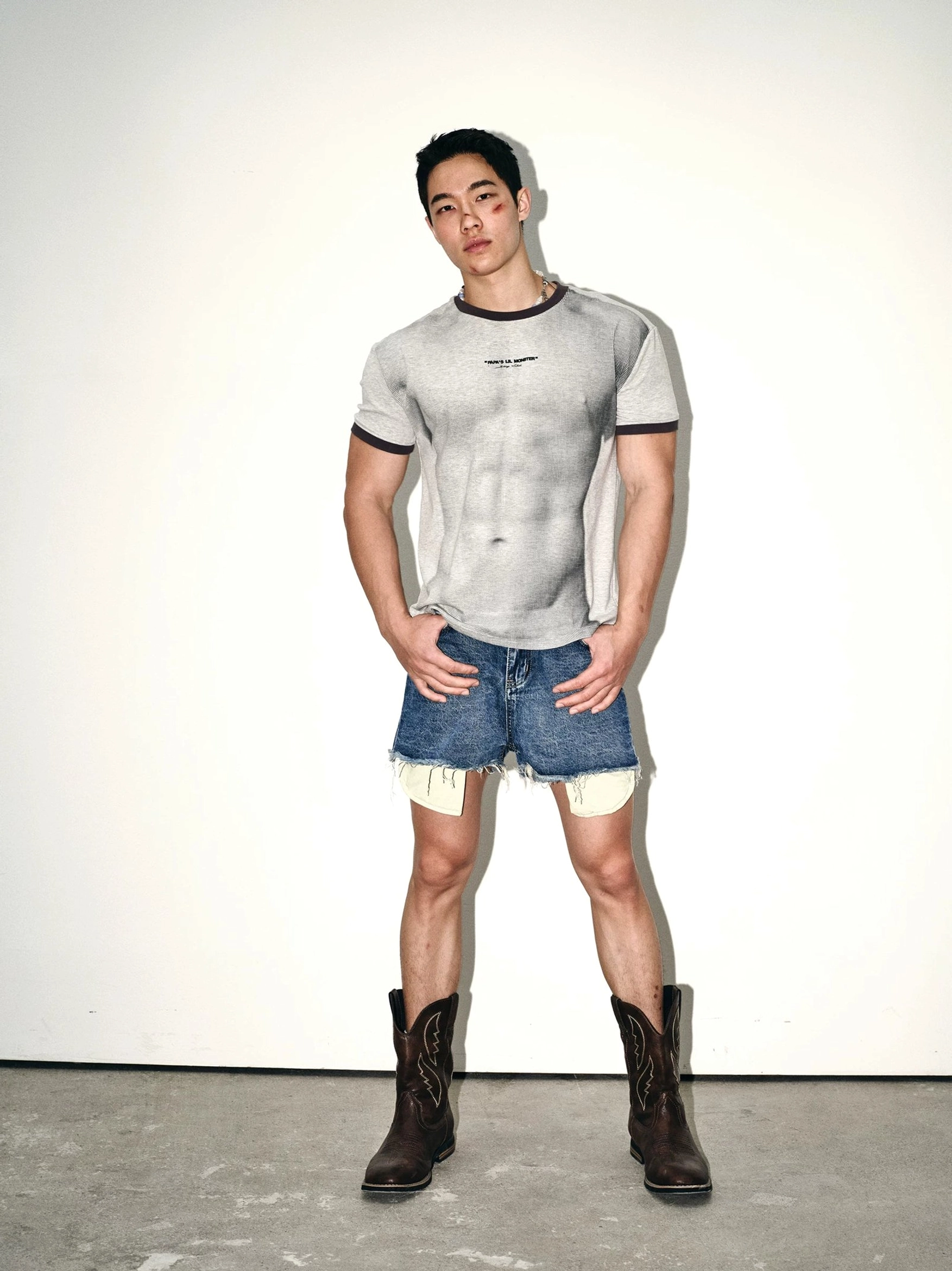 Gray contrast ringer tee with textured muscle pattern styling denim shorts and western cowboy boots streetwear outfit