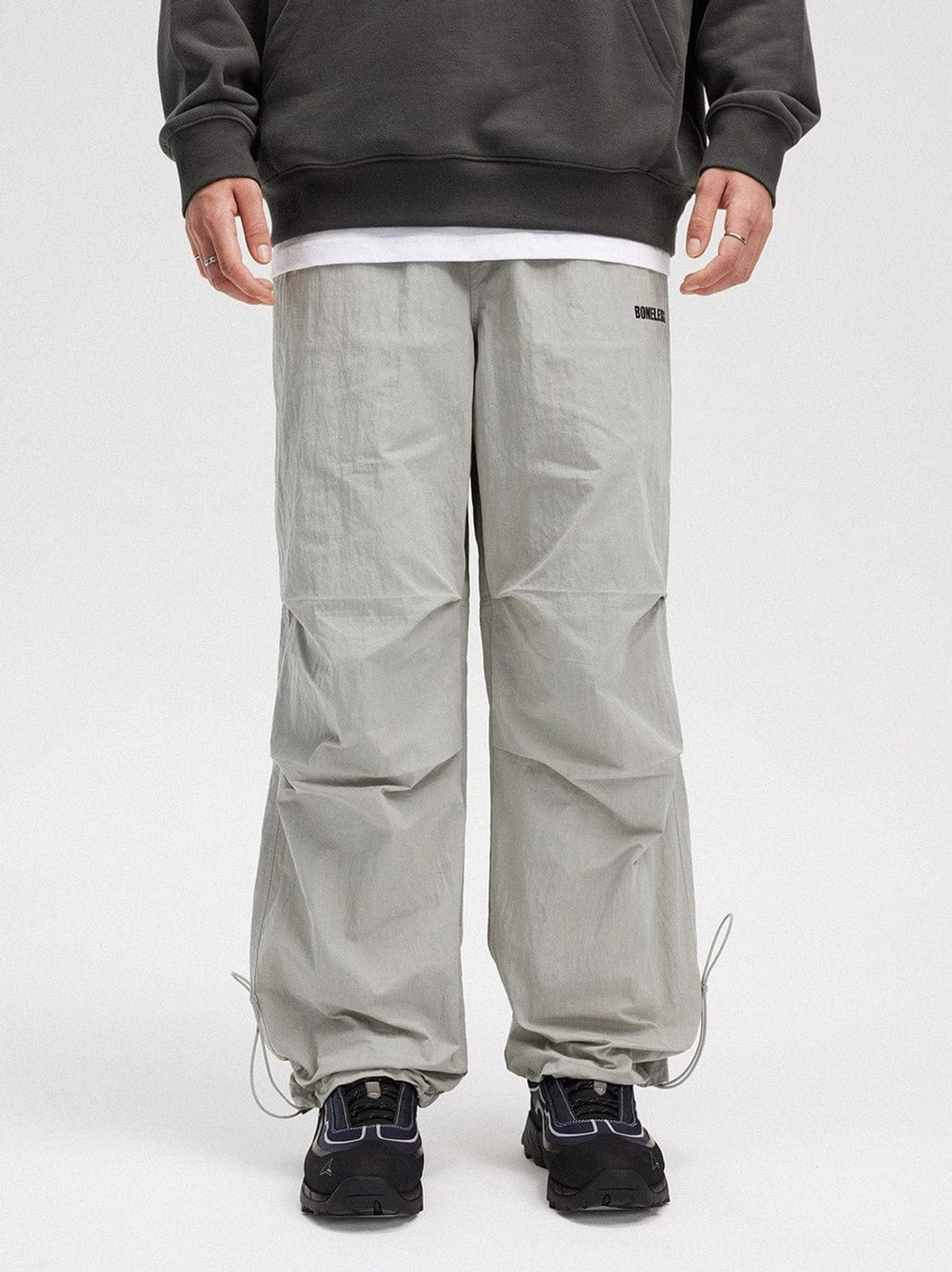 Gray crinkled wide-leg drawstring track pants shown from the front with relaxed Korean streetwear styling and sneakers