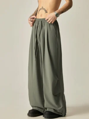 Gray green flowy wide leg drawstring pants for men shown from the front with a relaxed streetwear silhouette and elastic waistband