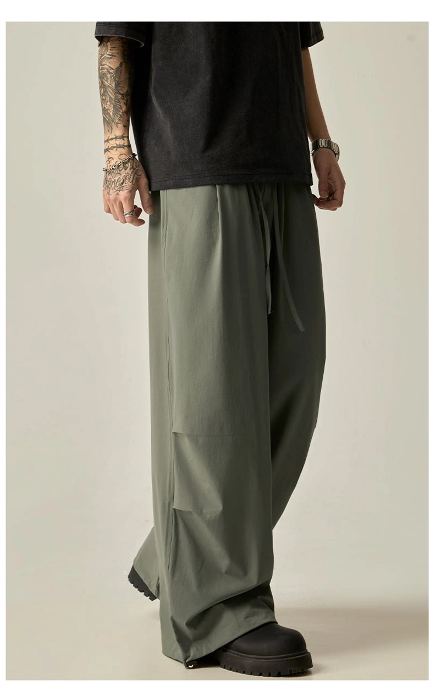 Gray green men's wide leg streetwear pants shown from a three-quarter angle with hidden side pockets and adjustable ankle drawstrings
