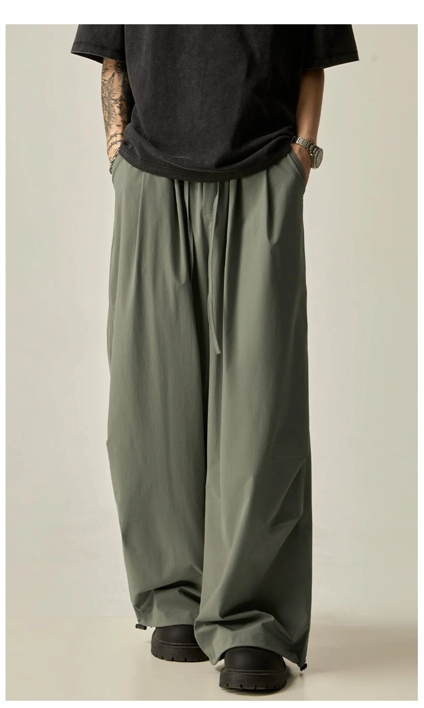 Gray green oversized wide leg drawstring pants for men shown from the rear with a soft lightweight fabric and elastic waist