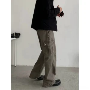 Rear side view of loose gray khaki relaxed straight leg cargo pants with side flap pockets styled with a black jacket and leather shoes