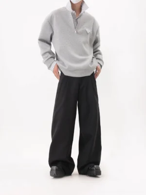 Oversized gray half-zip layered collar sweatshirt with hidden striped collar detail worn with black wide-leg trousers and platform shoes