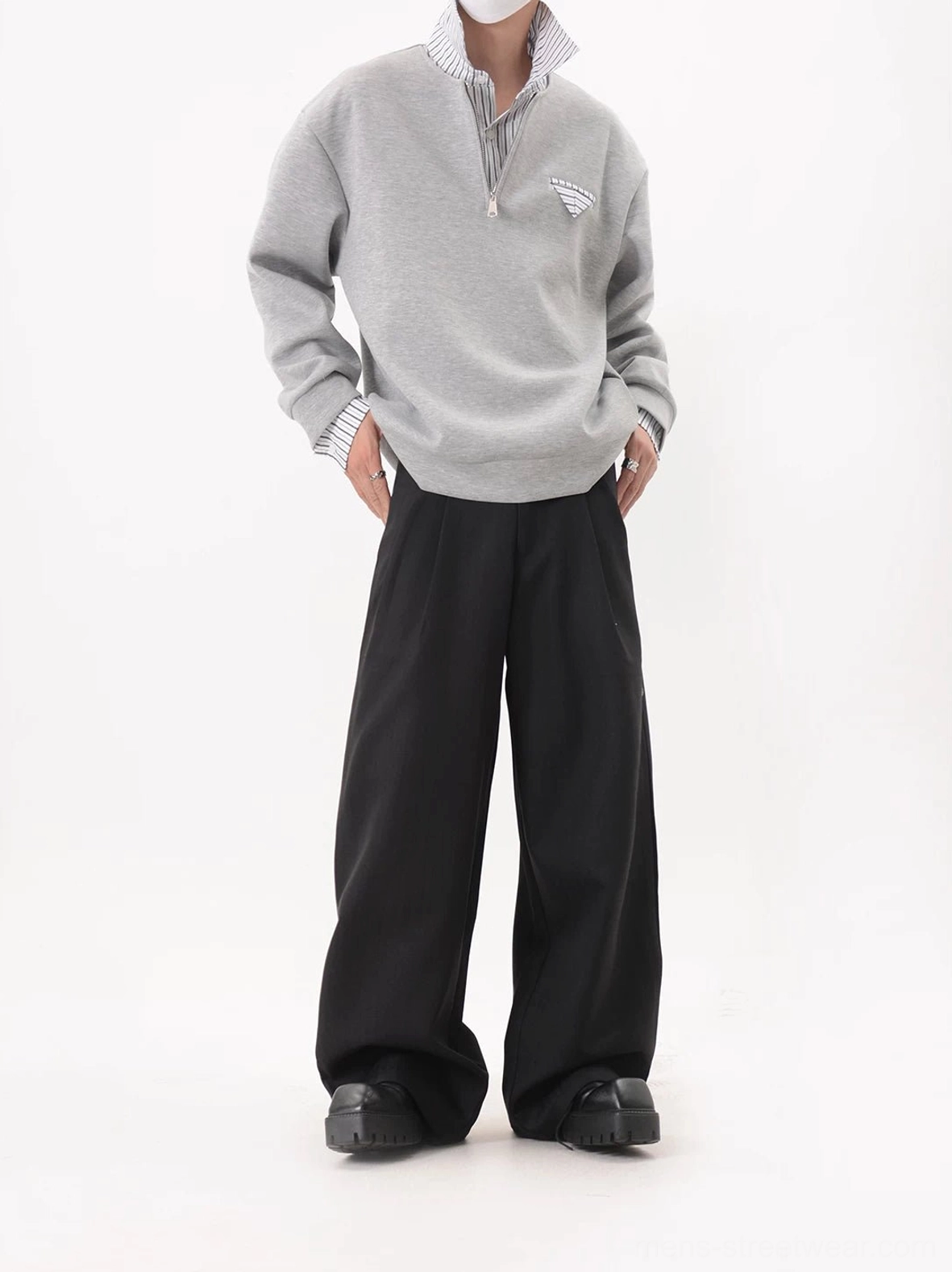 Oversized gray half-zip layered collar sweatshirt with hidden striped collar detail worn with black wide-leg trousers and platform shoes