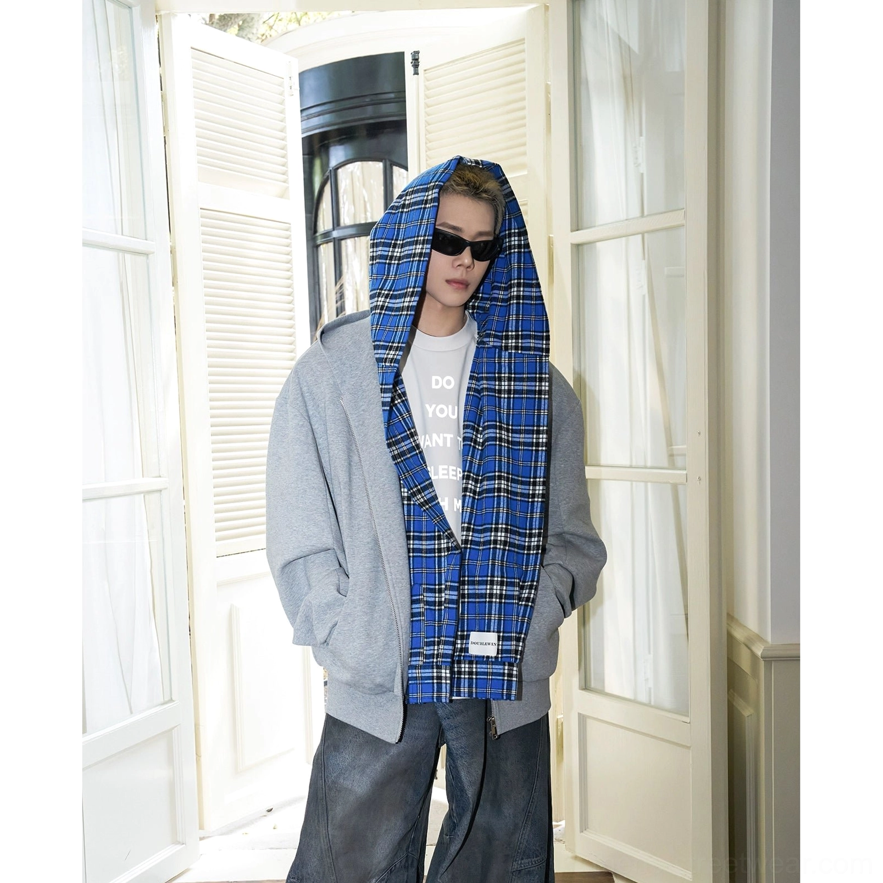 Male model standing in a gray oversized zip-up hoodie with blue plaid lining and hands in pockets, styled for contemporary Korean street fashion