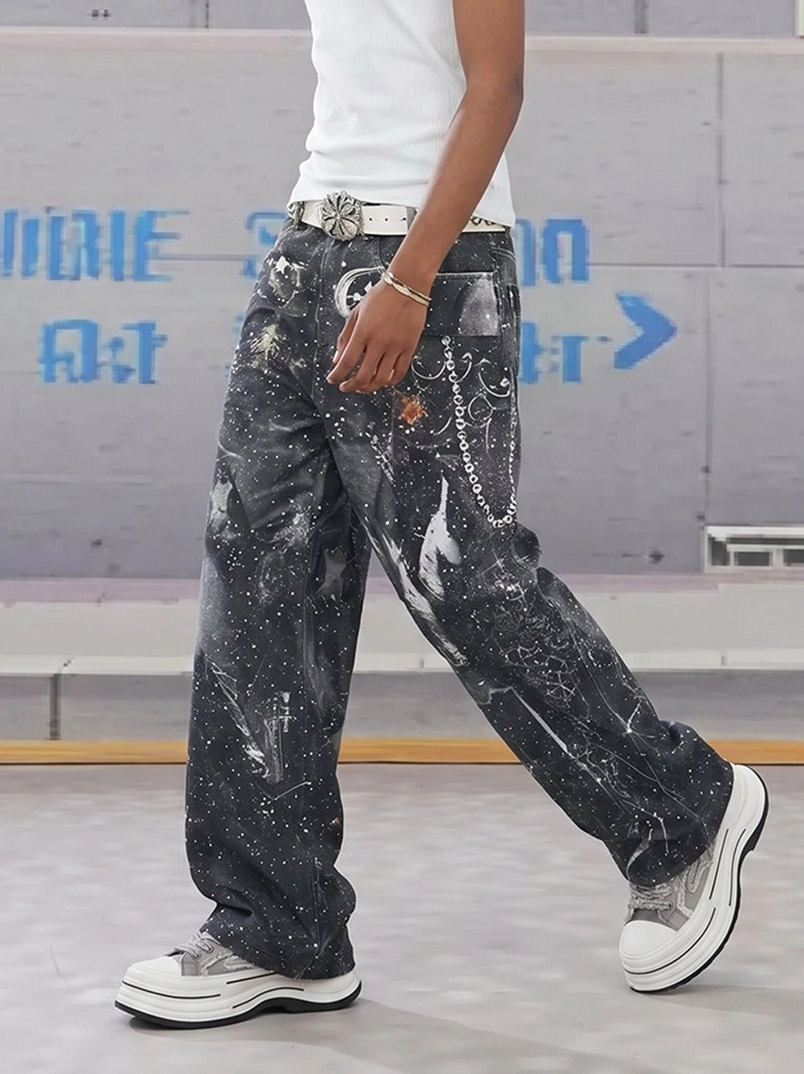 Gray platform street sneakers styled with a white tank top and splattered wide-leg denim pants in an industrial Seoul-inspired streetwear outfit