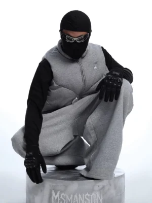 Front close-up of a gray quilted tech fleece streetwear jacket with high stand collar, full zipper, boxy silhouette, and structured padded panel design