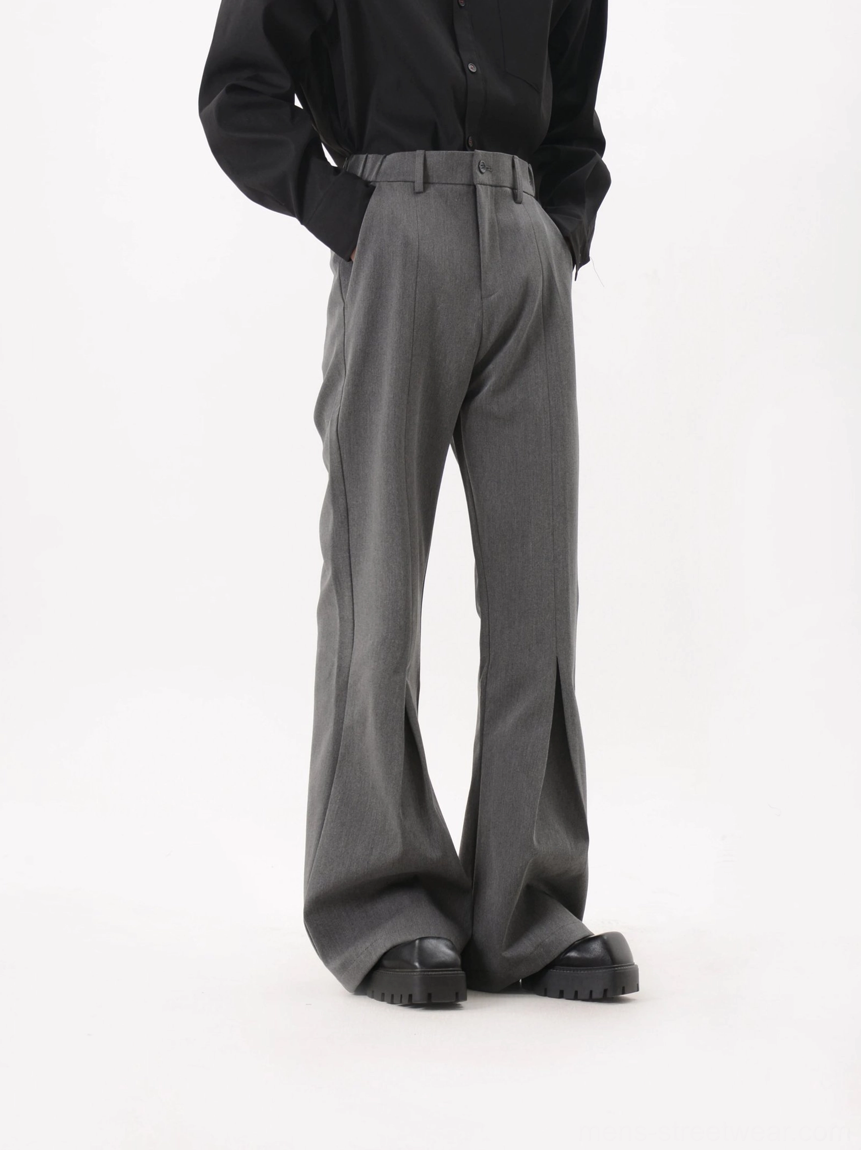 Side view of gray sculpted crease flared trousers showing structured waistband and flowing flared leg profile