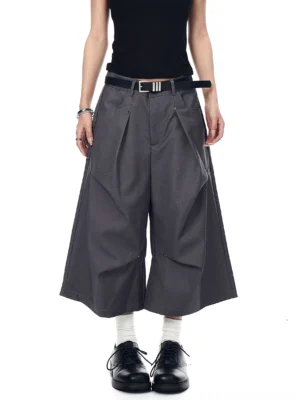 Gray studded pleated longline shorts shown from the front with a high-waisted wide-leg tailored streetwear silhouette