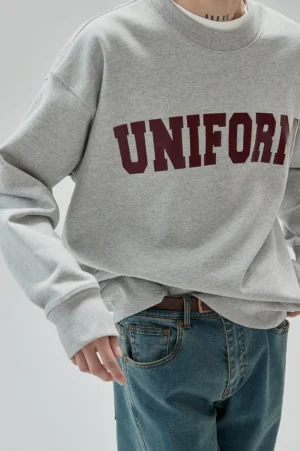 Close-up of gray cotton UNIFORM sweatshirt with ribbed crew neck maroon rubber lettering and relaxed streetwear fit