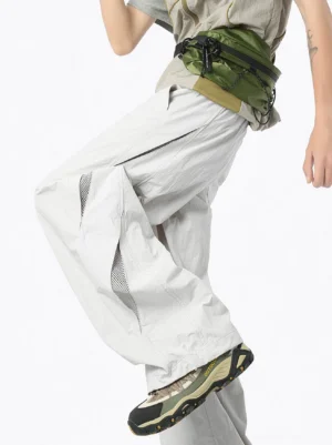 Gray vent mesh wide leg balloon pants with curved side ventilation panel in dynamic techwear outfit