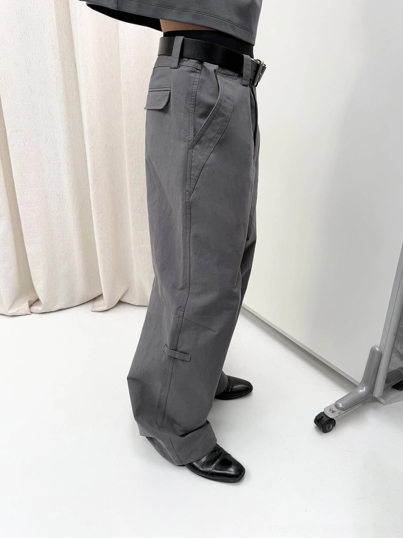 Gray washed cotton wide-leg trousers shown from the side with visible tailored seams, side pockets, and a loose streetwear cut