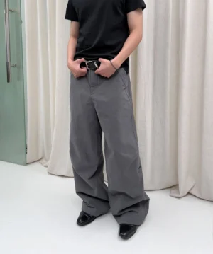 Gray washed wide-leg trousers shown in a full front view with a relaxed silhouette, black leather belt, and formal-inspired shoes