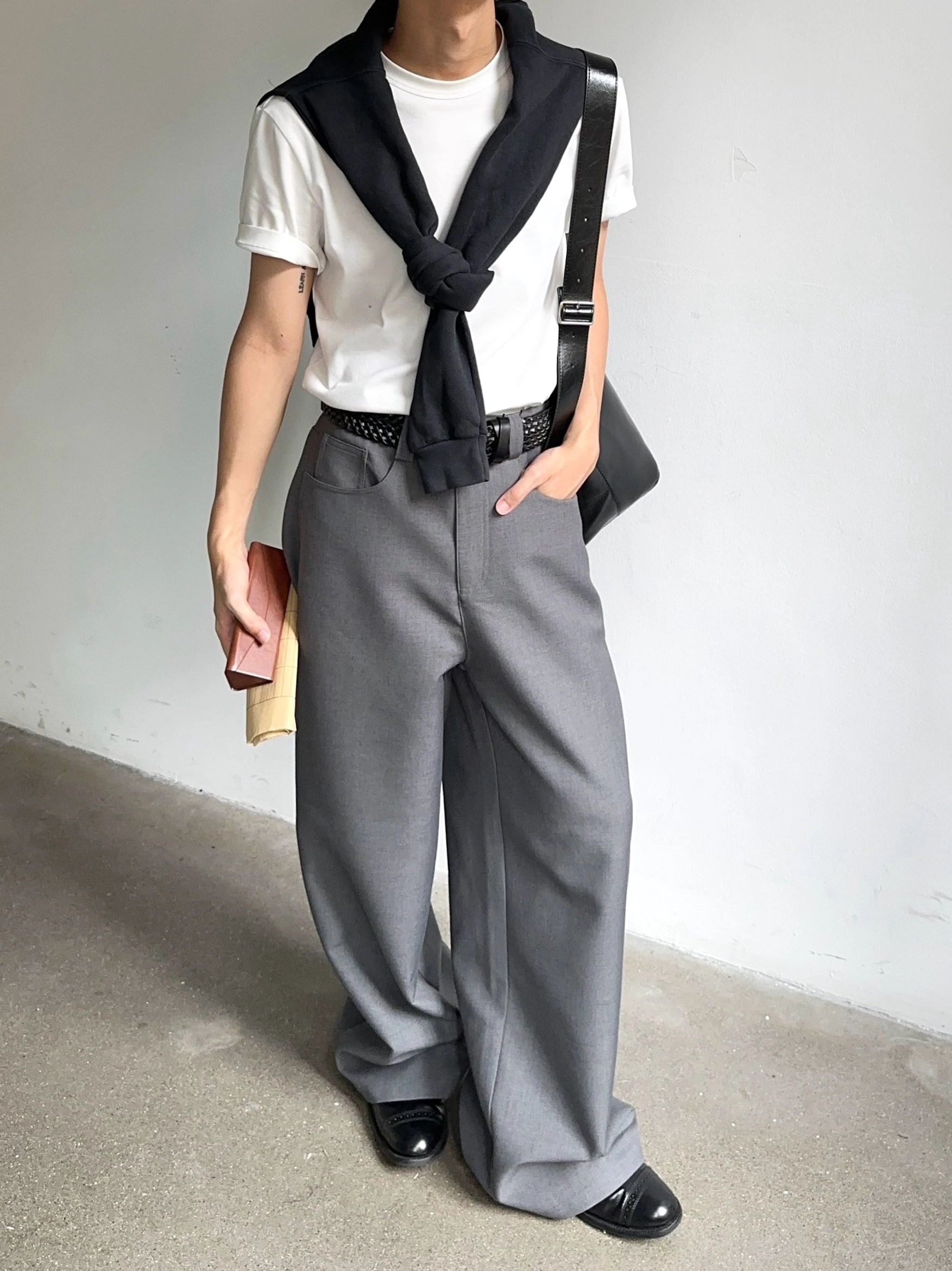 Gray wide-leg tailored trousers shown from the side with a soft drape, leather belt styling, and formal casual streetwear look