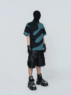 Front three-quarter view of an Acubi-inspired green half-zip streetwear tee showing the quarter-zip collar, curved teal stripes, black panels, and boxy oversized silhouette