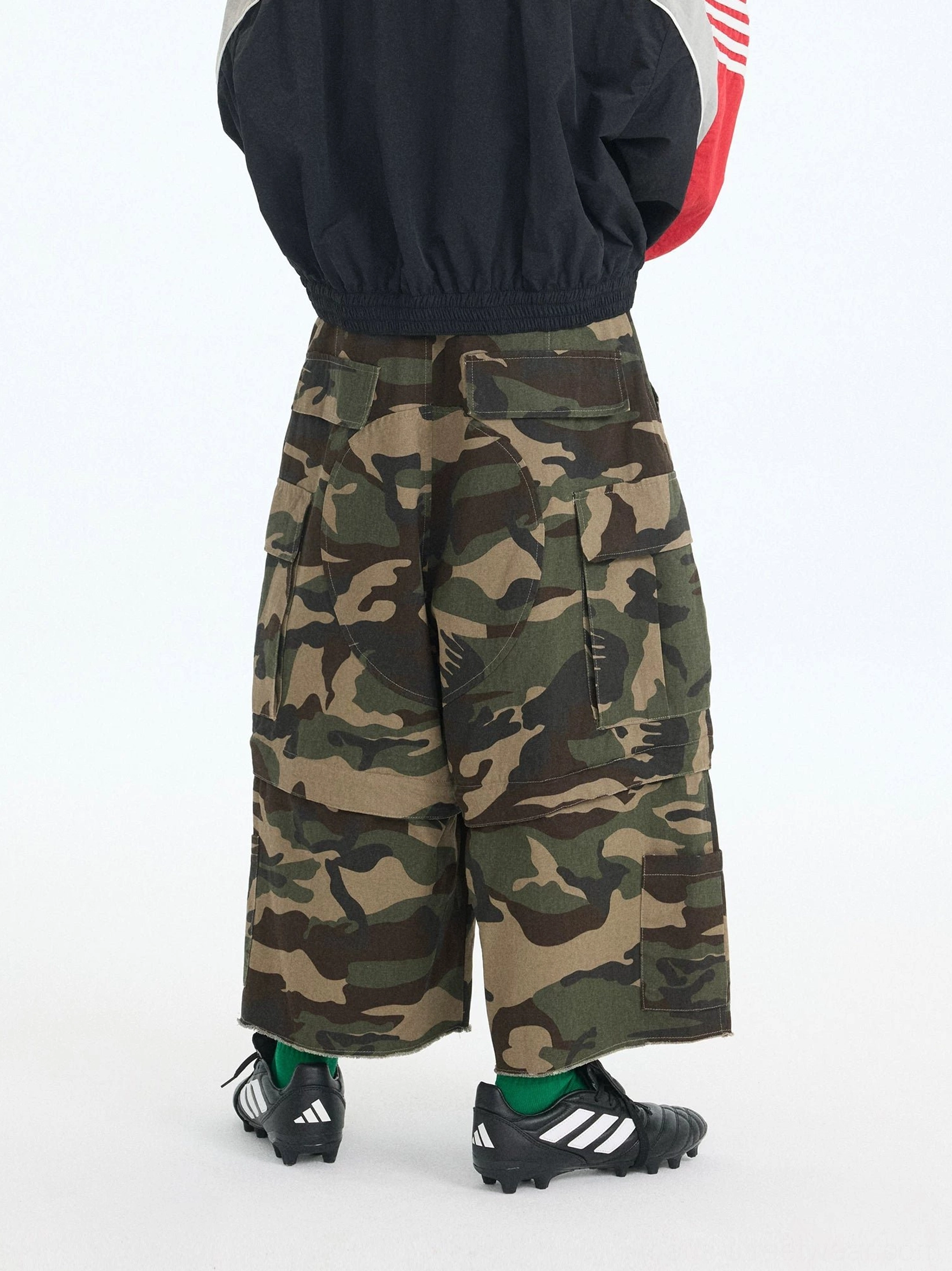Green camouflage convertible zip-off cargo pants with oversized utility fit, detachable lower legs, adjustable waist straps, and multiple cargo pockets