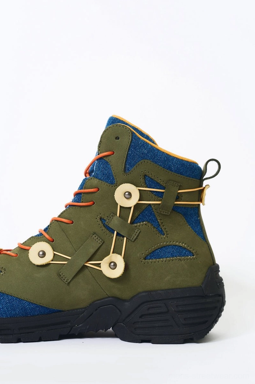 Single green denim and suede outdoor hiking boot shown in side profile with rear pull tab, buckle lacing system, and thick black rugged outsole