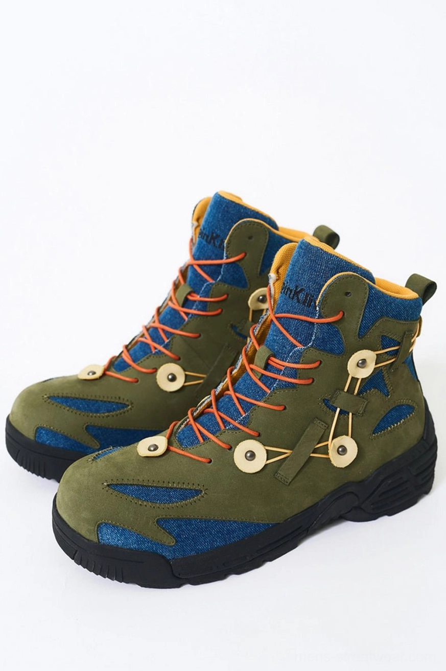 Green denim and suede outdoor hiking boots with orange round laces, circular buckle details, and thick black rugged anti-slip outsole shown from a front three-quarter view