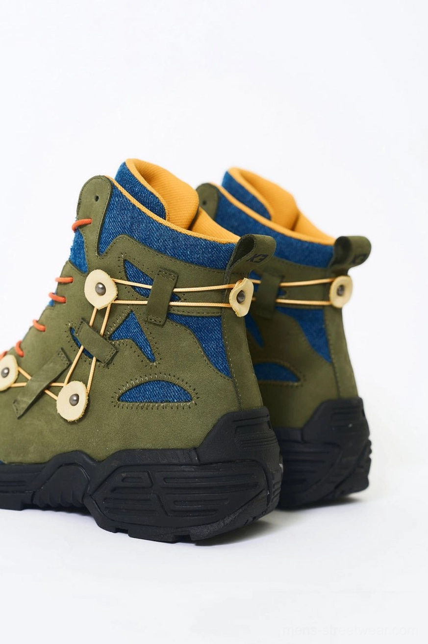 Rear three-quarter view of green denim and suede hiking boots with yellow collars, circular rear fastening details, and thick black anti-slip soles