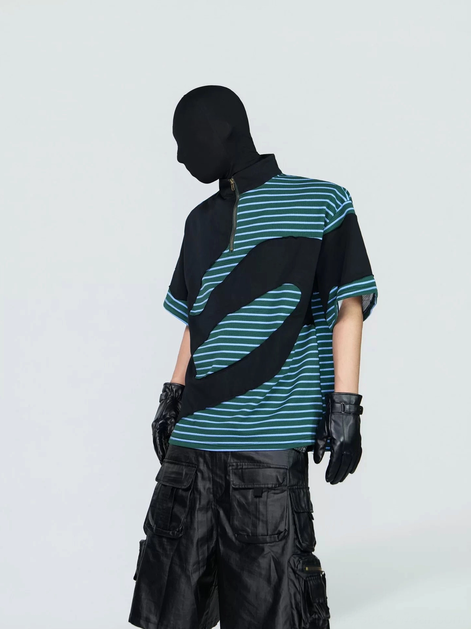 Left three-quarter view of a green teal and black half-zip striped tech tee with curved wave color blocking, mock neck, wide sleeves, and relaxed Korean streetwear fit