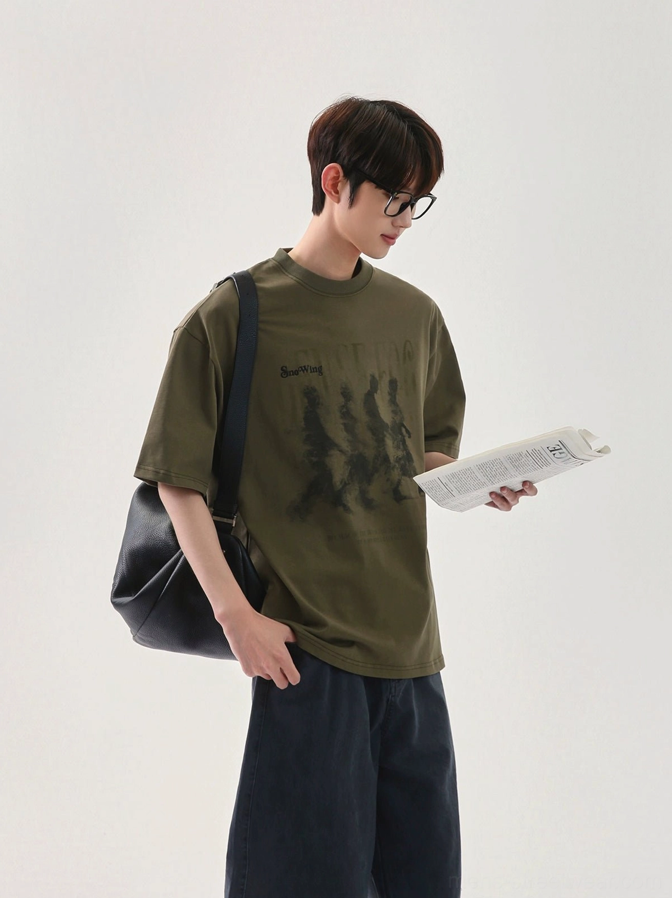 Army green oversized graphic T-shirt with monochrome vintage marching figure print, dropped shoulders, and casual East Asian streetwear fit