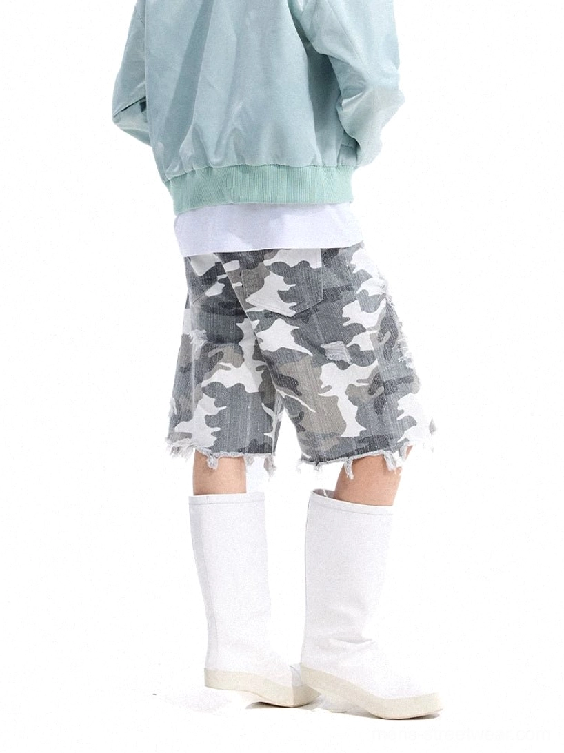 Right rear three-quarter view of grey camouflage distressed denim shorts with wide legs, unfinished frayed hem, and relaxed Korean streetwear styling