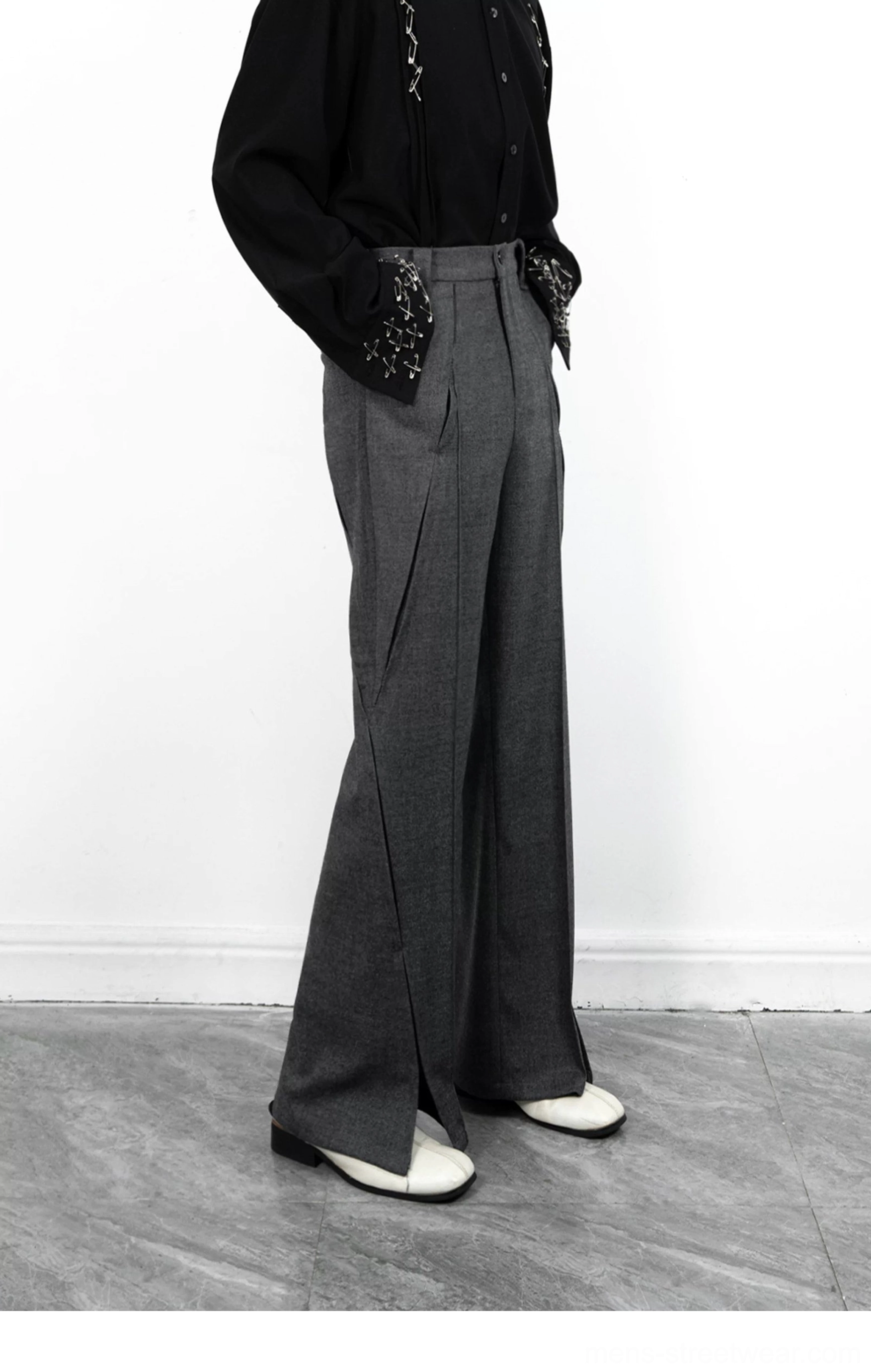 Side view of grey flared wide-leg tailored trousers with front pleats, flowing suiting fabric, and statement split hems