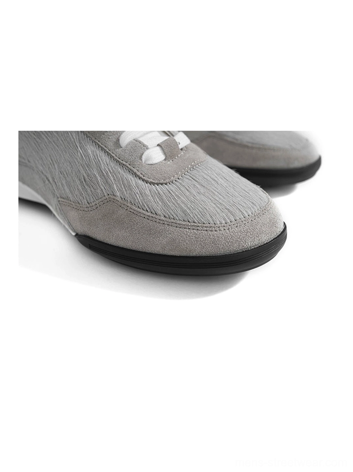 Front side close-up of a pair of grey fur-lined platform sneakers with fuzzy uppers, white laces, low-top shape, and black rubber outsoles