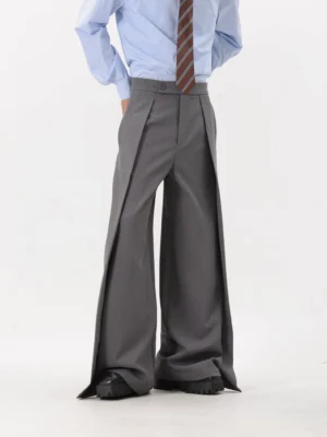 Grey high-waisted pleated ultra-wide leg trousers with draped side slit panels styled with a light blue shirt and striped tie