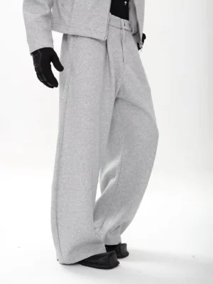 Side view of grey high-waisted pleated wide-leg sweatpants in soft fleece-style fabric styled with black gloves and leather loafers