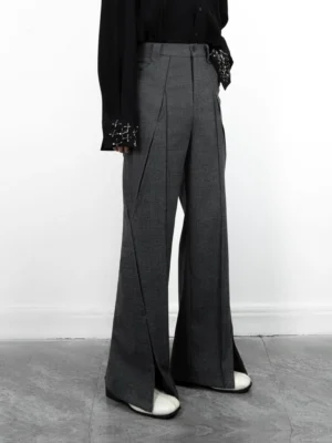 Front three-quarter view of grey high-waisted split-hem wide-leg tailored trousers styled with a black beaded blouse and white loafers