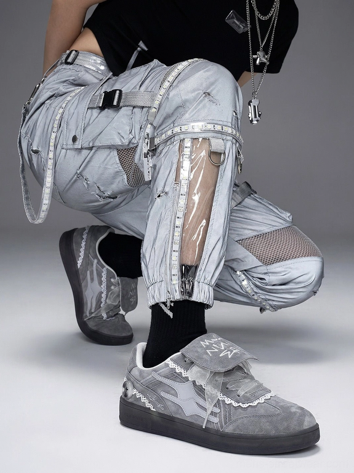 Grey lace-wrapped low-top trainers paired with technical cargo pants in a dark techwear outfit