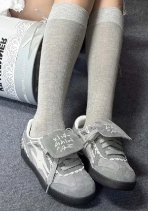 Grey lace-wrapped retro trainer sneakers worn with light grey knee-high socks in a top-down streetwear outfit view