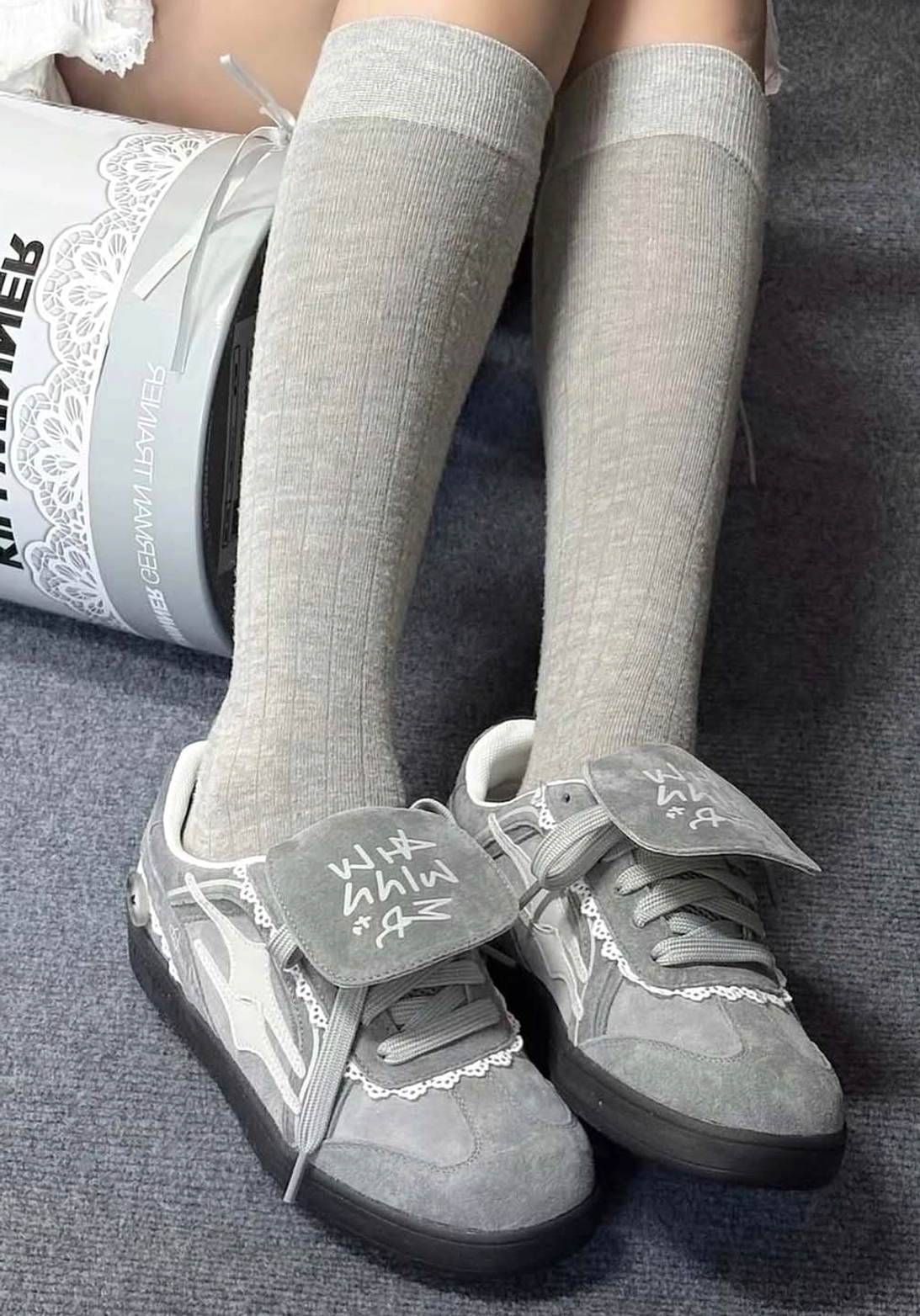 Grey lace-wrapped retro trainer sneakers worn with light grey knee-high socks in a top-down streetwear outfit view