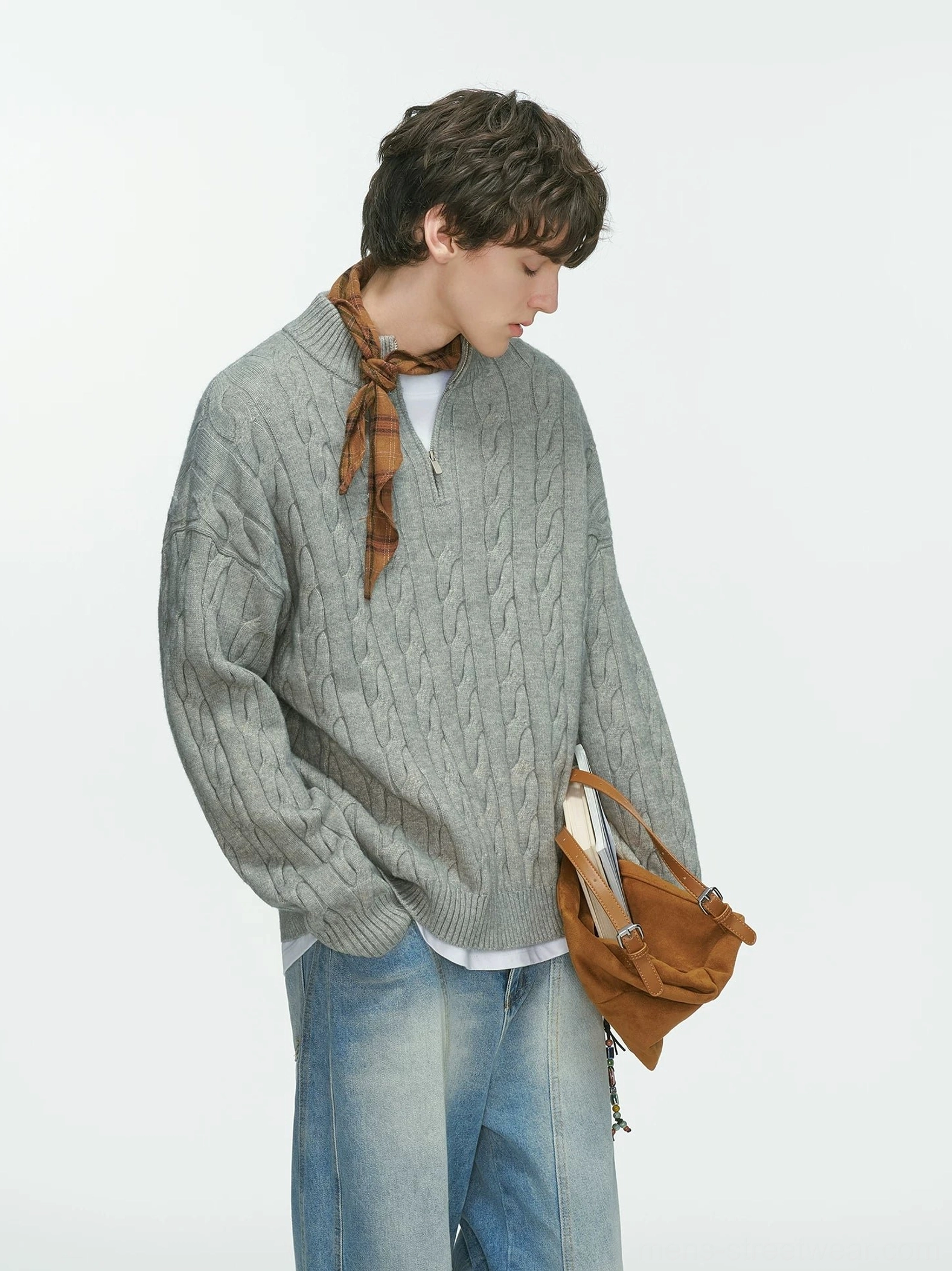 Grey oversized cable-knit quarter-zip sweater shown from the rear with light wash jeans, plaid scarf and brown shoulder bag