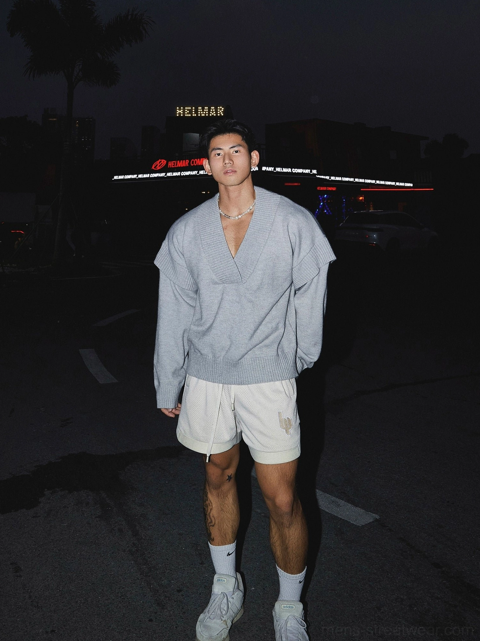 Grey oversized deep V-neck knit sweater styled with white shorts and sneakers for relaxed Seoul streetwear