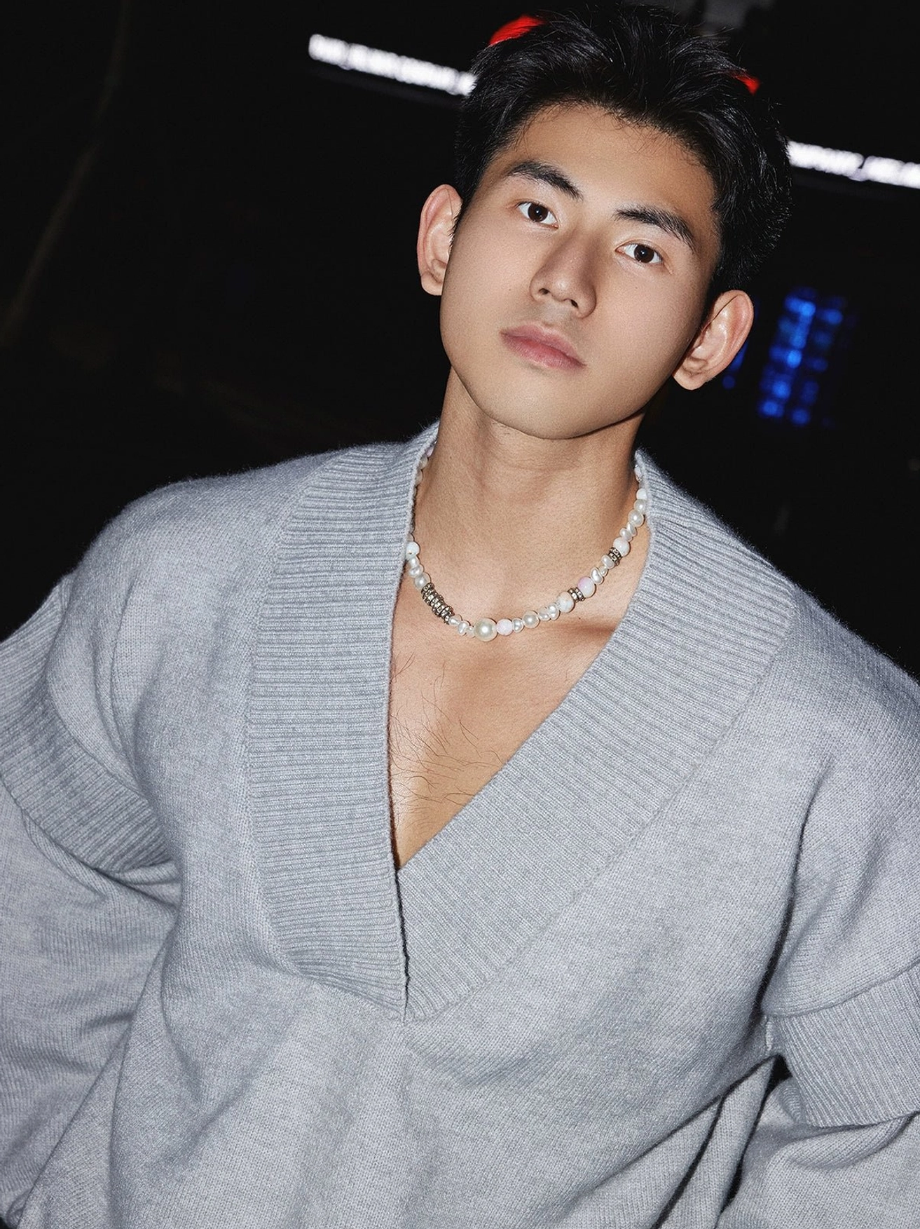 Close-up of grey oversized deep V-neck rib knit sweater styled with a pearl necklace for minimalist streetwear