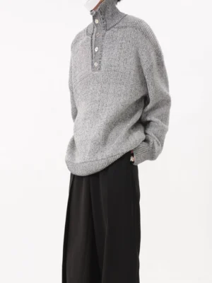 Side view of a grey oversized marled knit sweater featuring a chunky textured finish, curved hemline, loose silhouette, and ribbed trims