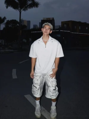 Young man wearing a heather grey oversized quarter-zip polo shirt with cargo shorts and sneakers in a Seoul-inspired urban streetwear outfit