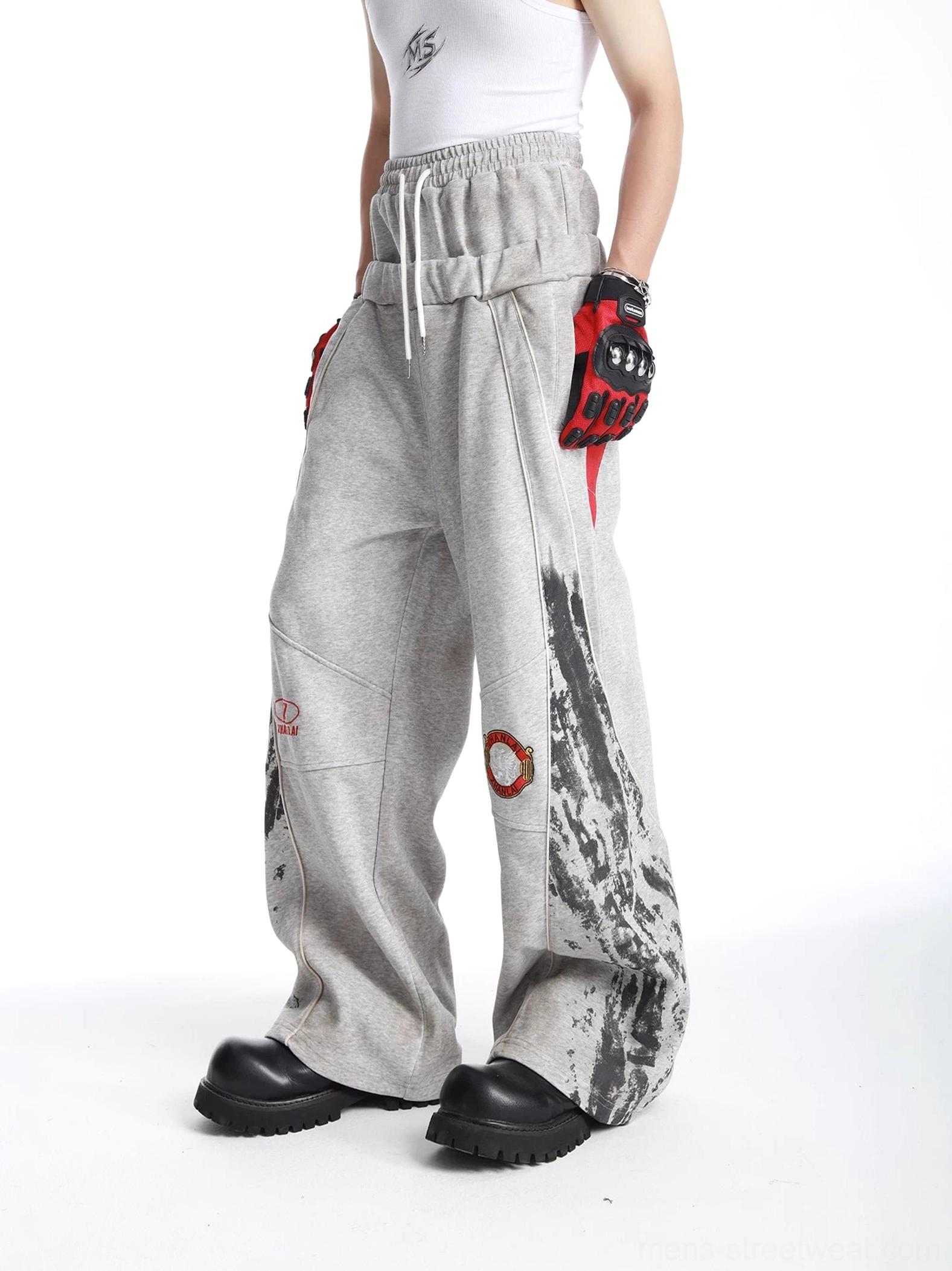 Grey oversized graphic sweatpants three-quarter side view showing black splatter print and red hip accent panel