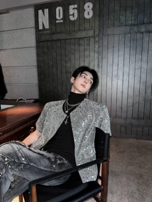 Grey sequin short sleeve streetwear open cardigan worn with black turtleneck and distressed dark denim in a retro bar setting