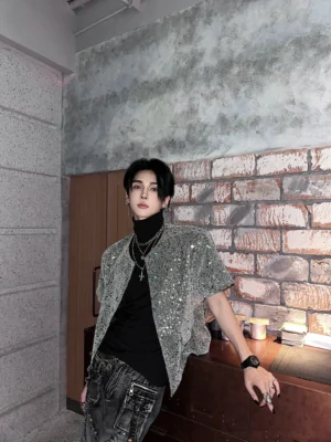 Three-quarter view of grey all-over sequin short sleeve open cardigan with black top and layered silver necklaces
