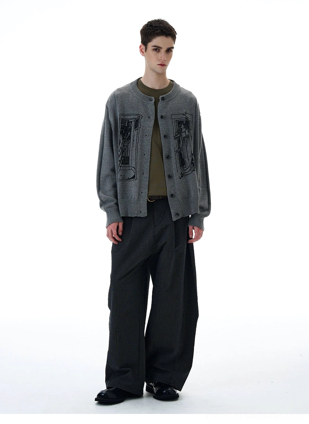 Male model wearing grey tarot window graphic knit cardigan with olive inner layer and striped wide-leg pants