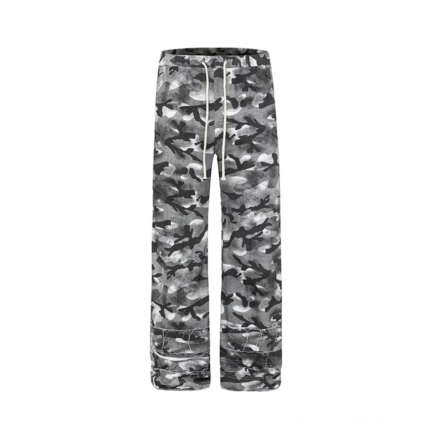 Flat lay front view of grey wide-leg camouflage cargo pants showing the elastic drawstring waist, side cargo pocket, monochrome camo print, and raw frayed hem